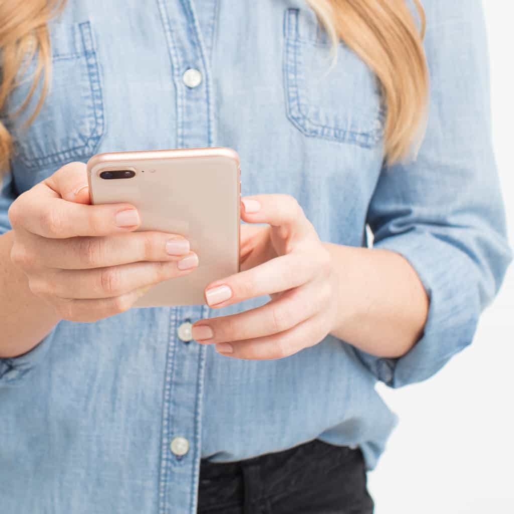 Woman checks her iphone to see if she is getting the right engagement on Instagram