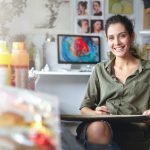 5 Tasks Every Service Business Owner Should Outsource In 2025 Smiling female artist wearing casual clothes sitting in her cabinet with sketches and colorful paint, having happy expression while being glad to create beautiful picture. Painter working in workshop