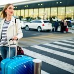 Everything You Need to Know About Airport Shuttle Options Stunning blonde lady with blue and white suitcases stands before