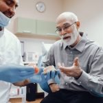 How Acrylic Dentures Have Become a Practical Solution for Missing Teeth in Kansas City Handsome old man talking to the dendist. Two men in the dentist's office. The doctor shows the patient dentures