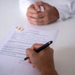 What Options You Have When Divorce Papers Are Refused Hands of wife, husband signing decree of divorce, dissolution, canceling marriage, legal separation documents, filing divorce papers or premarital agreement prepared by lawyer. Wedding ring